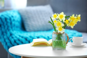 Yellow narcissus on white table in room interior